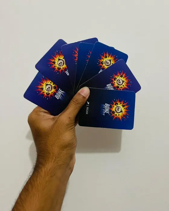 A hand fanning out Bone Blast cards, showing the blue card backs
